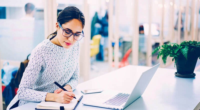 page_blog_standard_2 Frau sitzt vor dem Laptop und notiert etwas